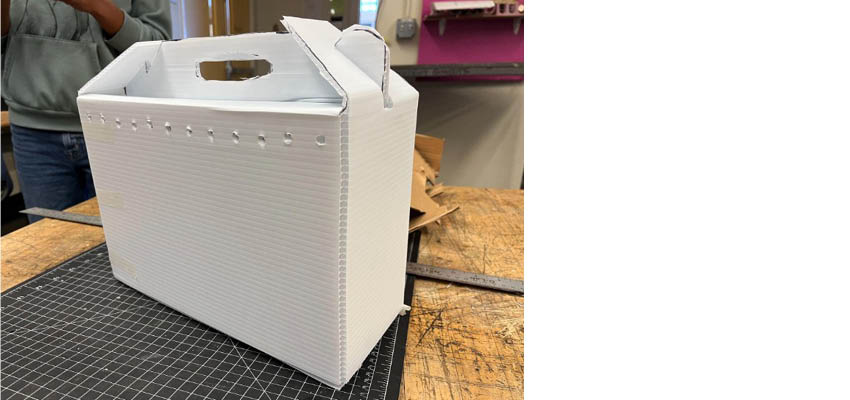 A white corrugated box with handles on a table.