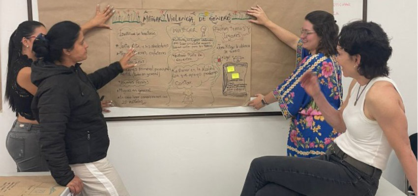 Two women at left, one woman at right, brown paper with notes on a well between them.