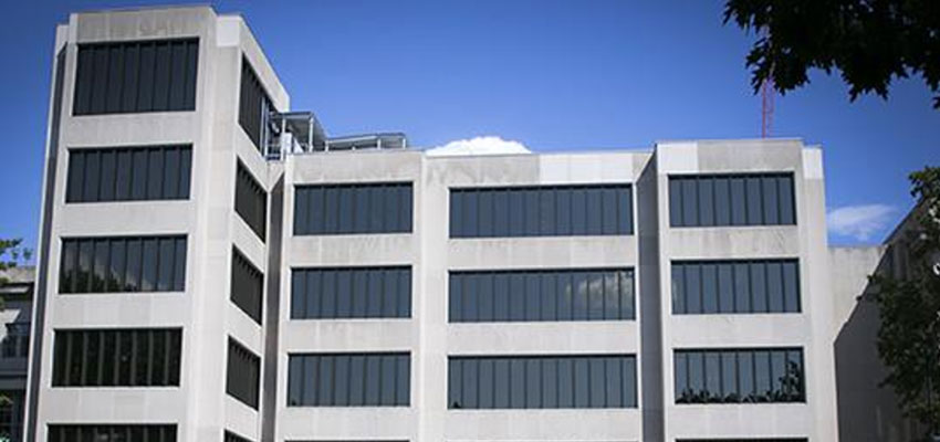 Multistory concrete building and windows against a blue sky.