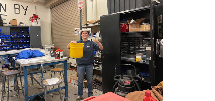 Man in workshop holding yellow bucket.