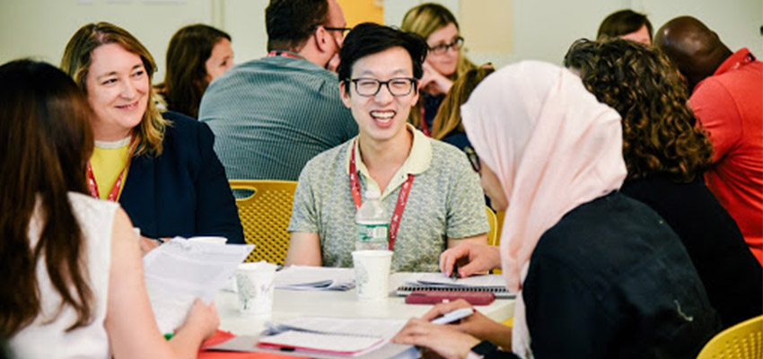 Smiling group of people at a table in the 2019 Inclusive Innovation professional education course discussing a case study of a real-world agricultural challenge. 