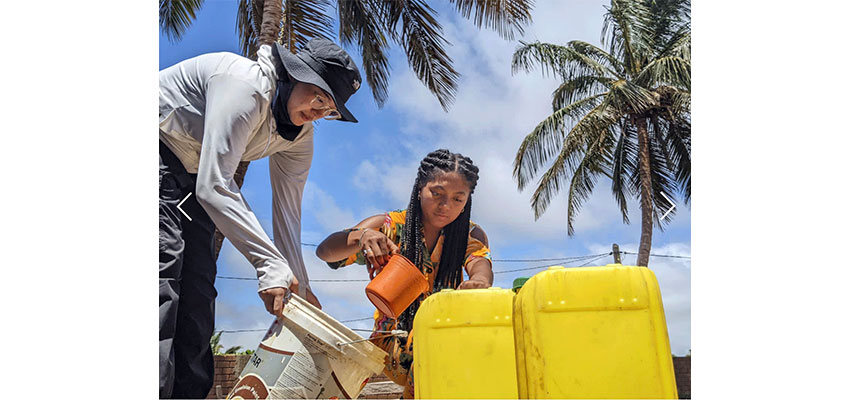 Two people filling a yellow jerry can.