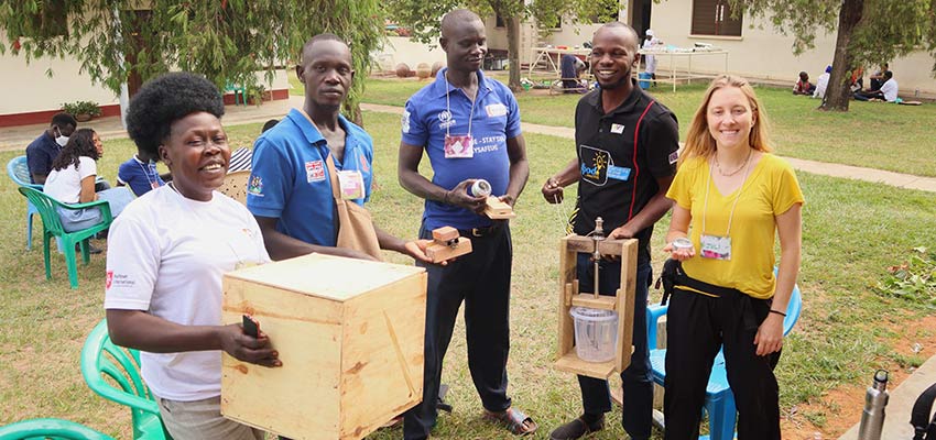 Four people standing and smiling holding tools they have made.